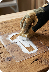 рабочий наносит изображение с помощью трафарета из прозрачного пластика